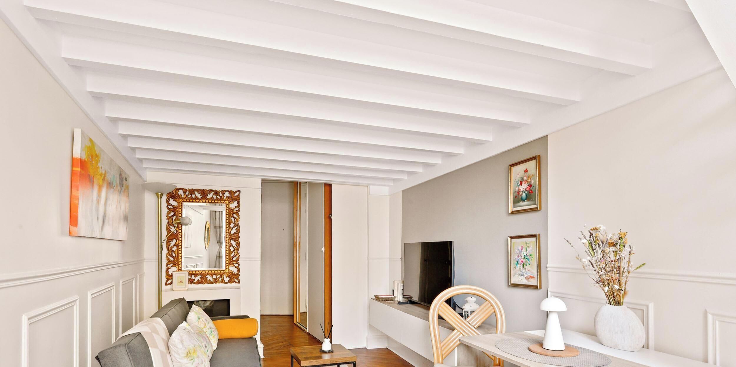 A modern interior with a sofa, a dining table, and a television.