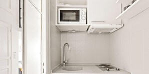 Une salle de bain compacte équipée d’un four à micro-ondes encastré, d’une douche et d’un petit lavabo.