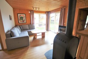 Ein modernes Wohnzimmer mit einer Eckcouch, Holzbalkendecke und einem großen Kamin.