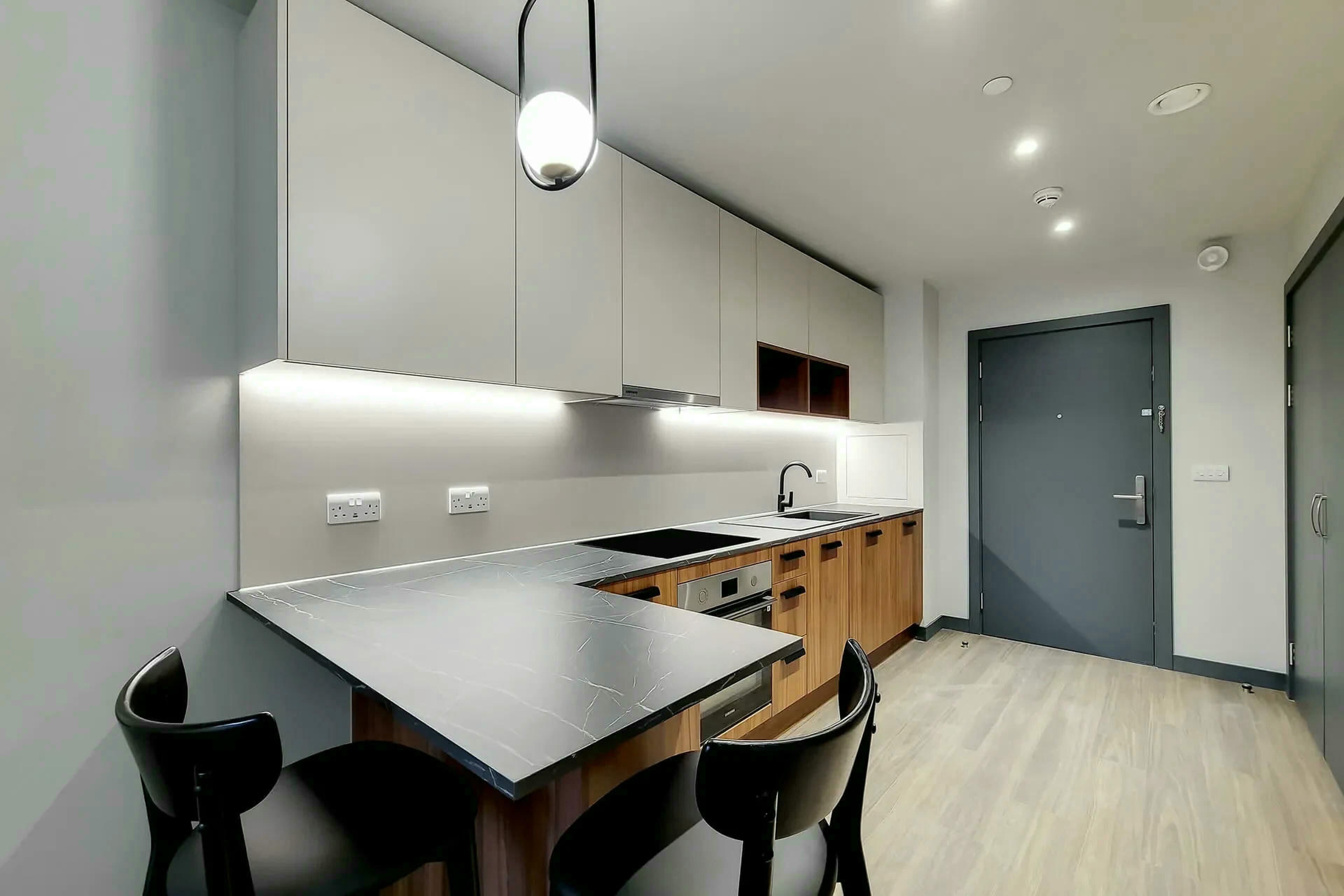 A modern kitchen with a central island, wooden cabinets, and a dark countertop.