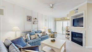 A living room with a sofa set, a coffee table, a fireplace, and a TV mounted on the wall. - Lorelei II 405 - Your perfect Ocean City getaway! (Ocean City)