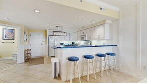 A modern kitchen with white cabinets, a blue countertop, and four bar stools. - Lorelei II 405 - Your perfect Ocean City getaway! (Ocean City)