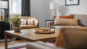 Una sala de estar moderna con un sofá, un sillón y una mesa de centro con una planta.