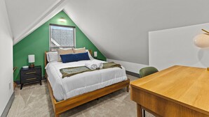 Un dormitorio con cama, mesita de noche, lámpara y vistas al exterior.