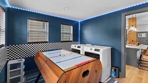 Una habitación con mesa de fútbol de mesa, lavadora y lavabo.