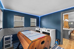 Ein Zimmer mit Tischfußball, einer Waschmaschine und einem Waschbecken.