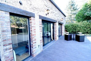 A modern building with large glass doors, a brick facade, and outdoor seating. - Domaine de L'Olymp (Cornant)