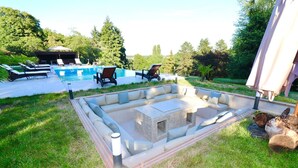 Un cortile con piscina, un braciere integrato e area salotto all'aperto.