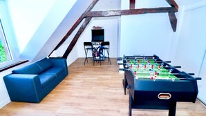 Una stanza con un tavolo da calcio, un divano blu e vista su un balcone.