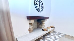 Un camino con base in pietra, una mensola in legno e un orologio sopra.