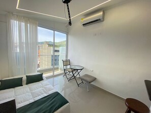 Ein Hotelzimmer mit einem Bett, einem kleinen Tisch, einem Stuhl und Blick auf die Stadt.