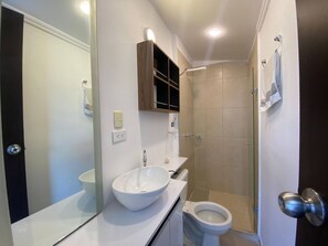 Ein Badezimmer mit weißem Waschbecken, Toilette und Duschbereich.
