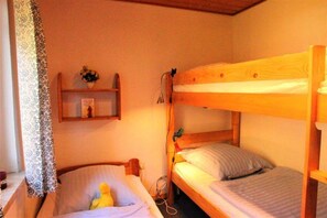 A bunk bed room with a wooden headboard, a bedside table with a lamp, and a shelf with a vase. - Urlaub im Grunen - Doppelbungalow mit Terrasse im Ferienpark Mirow (Mirow)