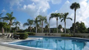 Ein Swimmingpool mit Liegestühlen, Palmen und blauem Himmel.