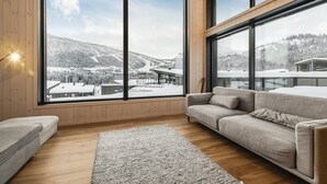 Una sala de estar moderna con ventanas grandes, un sofá y una alfombra.