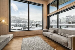 Ein modernes Wohnzimmer mit großen Fenstern, einem Sofa und einem Teppich.