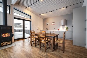 A modern kitchen with a wooden dining table and chairs, a built-in stove, and a view through the glass door. - Modern family home in Hemsedal - spectacular views! (Hemsedal)