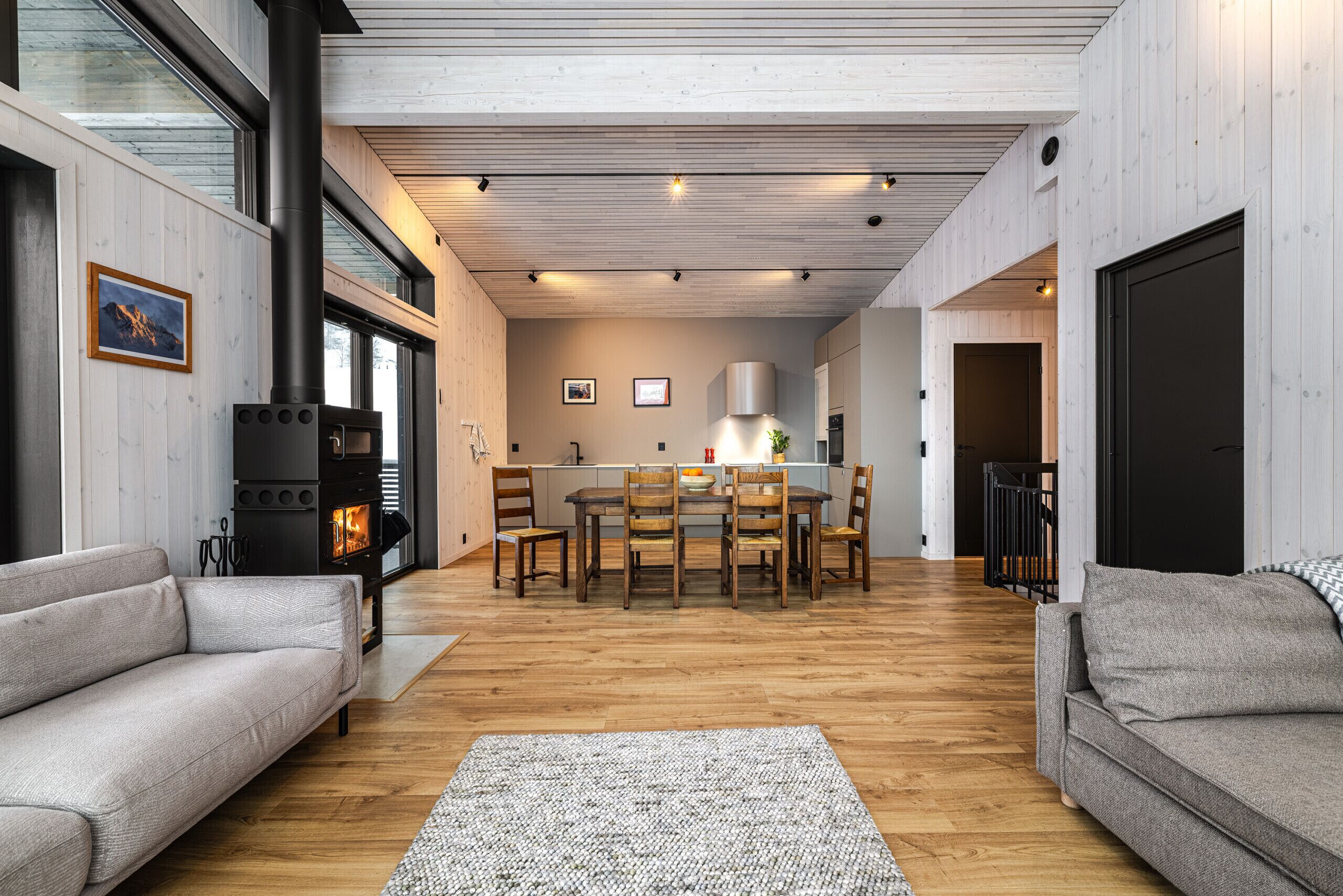 Un intérieur moderne avec un espace de salle à manger central, un plancher en bois et une cheminée bien visible.
