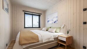 Un dormitorio con cama, mesita de noche, lámpara y ventana con vistas.