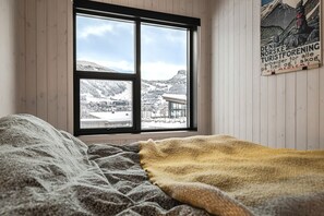 A bedroom with a large window offering a view of a snowy landscape. - Modern family home in Hemsedal - spectacular views! (Hemsedal)