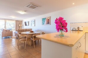 A modern kitchen with a dining area, a coffee machine, and a vase with flowers. - Blue Waters- Riverview Escape for the whole family (Kalbarri)