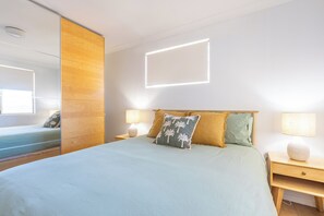 A modern bedroom with a large bed, two bedside tables, a mirror, and a view of the sea. - Blue Waters- Riverview Escape for the whole family (Kalbarri)