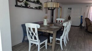 En matplats med ett träbord, vita stolar, en klocka och en hängande lampa.