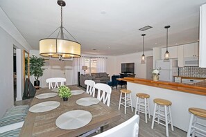A modern kitchen with white cabinets, a wooden countertop, and a bar area with stools. - Cozy house with heated pool near the beach (Lighthouse Point)