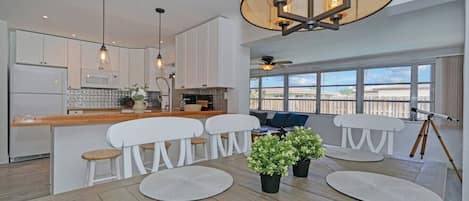 A modern kitchen with white cabinets, a wooden countertop, and pendant lighting.