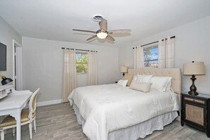 A bedroom with a bed, two bedside tables, a desk, a chair, a ceiling fan, and curtains. - Cozy house with heated pool near the beach (Lighthouse Point)