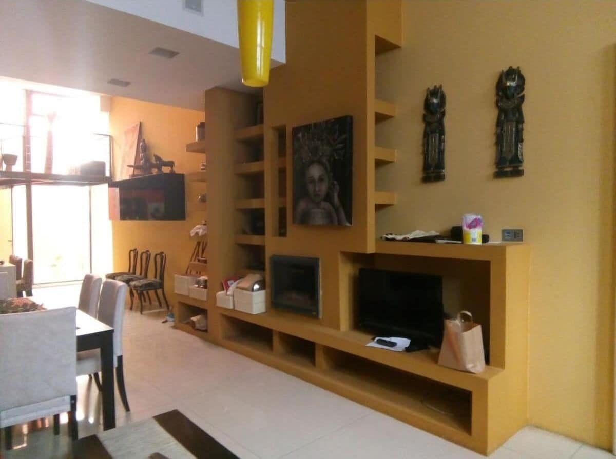 Un salon équipé d’un téléviseur, d’étagères et d’un coin repas avec des chaises et une table.