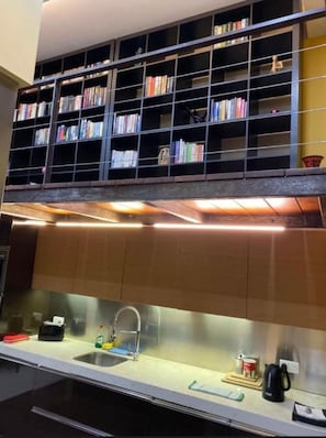 Eine Küche mit einem fest eingebauten Bücherregal über der Arbeitsplatte.