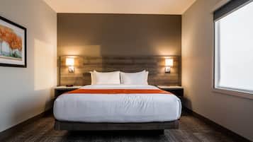 A hotel room with a large bed, two bedside tables, a headboard, and a window.