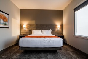 A hotel room with a large bed, two bedside tables, a headboard, and a window. - Amsterdam Inn & Suites Grand Falls, an Ascend Collection Hotel (Grand Falls)