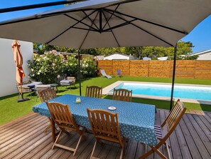 Eine Terrasse mit Tisch und Stühlen, einem Pool und einem Holzzaun im Hintergrund.