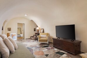A cozy living room with a sofa, armchair, and a television on a brick cabinet.