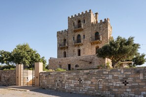 A historic stone tower with multiple windows and a gated entrance. - Prezerakos Tower (East Mani)