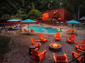 Un jardin avec une piscine, un espace salon extérieur et un foyer.