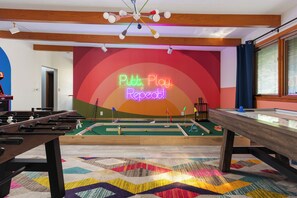 A room with a foosball table, pool table, and a colorful carpet. - Htd Pool, Sports Court, Sauna, Hot Tub, Arcade, Bowling, EV - 5 Acre Estate (Norton Shores)