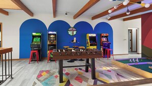 Una habitación con mesa de fútbol, juegos de arcade y mesa de billar.
