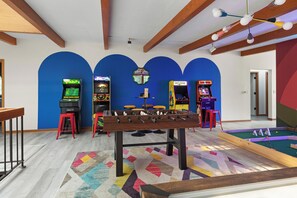 Ein Raum mit einem Kicker, Spielautomaten und einem Billardtisch.