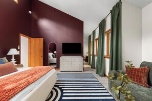 Ein Hotelzimmer mit Bett, Fernseher, Schminktisch und einem Fenster mit Vorhängen.
