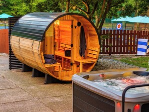 Une structure en forme de tonneau, faite de bois, comprenant un bain à remous et un espace détente.