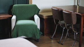 A room with a green chair, a wooden table, and four chairs. - Pleasant furnished studio with AC in vibrant Guadalajara neighborhood (Guadalajara)