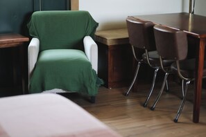 A room with a green chair, a wooden table, and four chairs. - Pleasant furnished studio with AC in vibrant Guadalajara neighborhood (Guadalajara)
