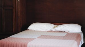 A single bed with a white and pink striped bedspread in a room with wooden walls and a door. - Pleasant furnished studio with AC in vibrant Guadalajara neighborhood (Guadalajara)