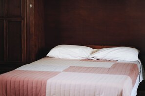 A single bed with a white and pink striped bedspread in a room with wooden walls and a door. - Pleasant furnished studio with AC in vibrant Guadalajara neighborhood (Guadalajara)