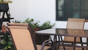 A round table with chairs, a potted plant, and a window with a grid pattern. - Pleasant furnished studio with AC in vibrant Guadalajara neighborhood (Guadalajara)