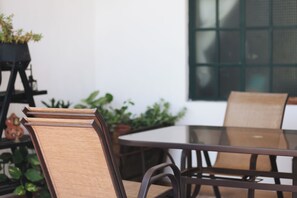 A round table with chairs, a potted plant, and a window with a grid pattern. - Pleasant furnished studio with AC in vibrant Guadalajara neighborhood (Guadalajara)