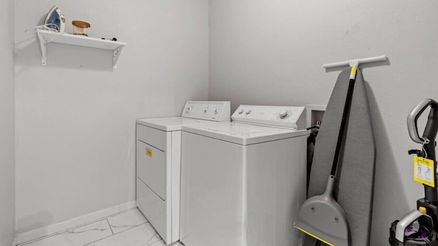A laundry room with a washing machine, dryer, ironing board, and a shelf with a few items. - Stylish 3-Bedroom Austin Home in a Seriously Convenient Location (Austin)